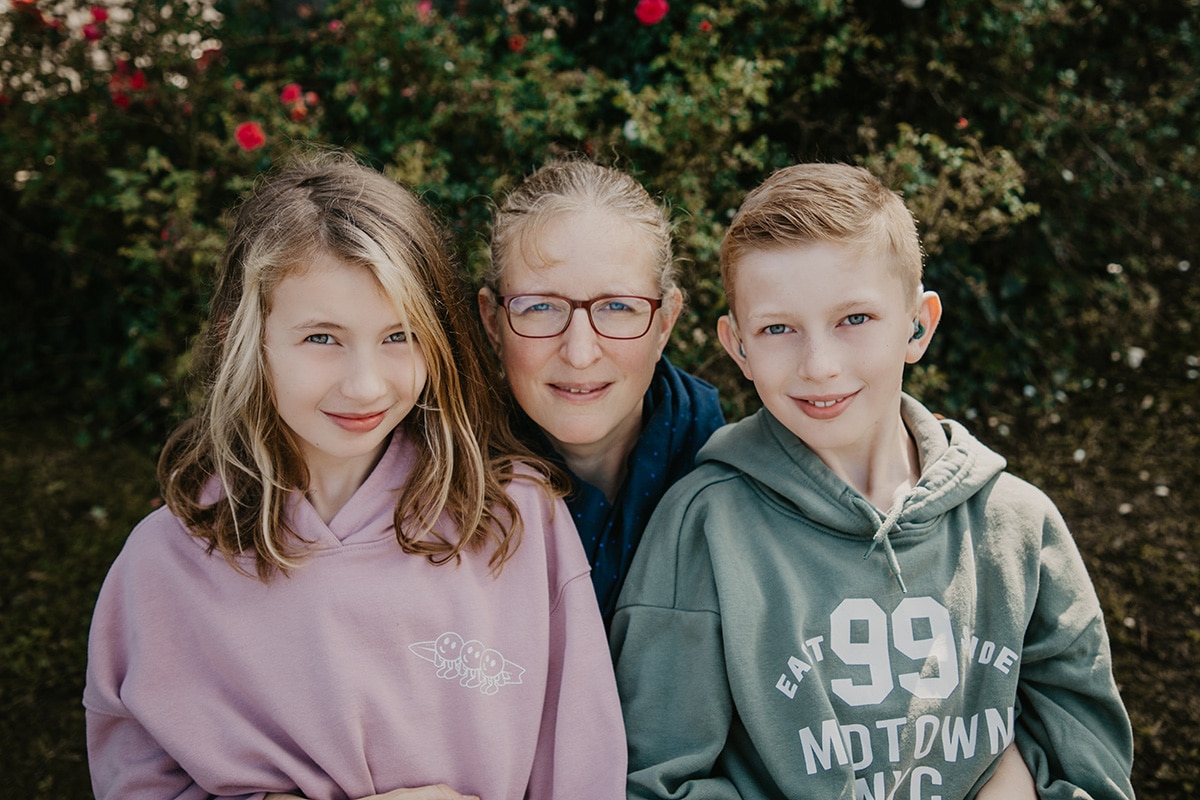 A woman embraces two children while posing for a picture.
