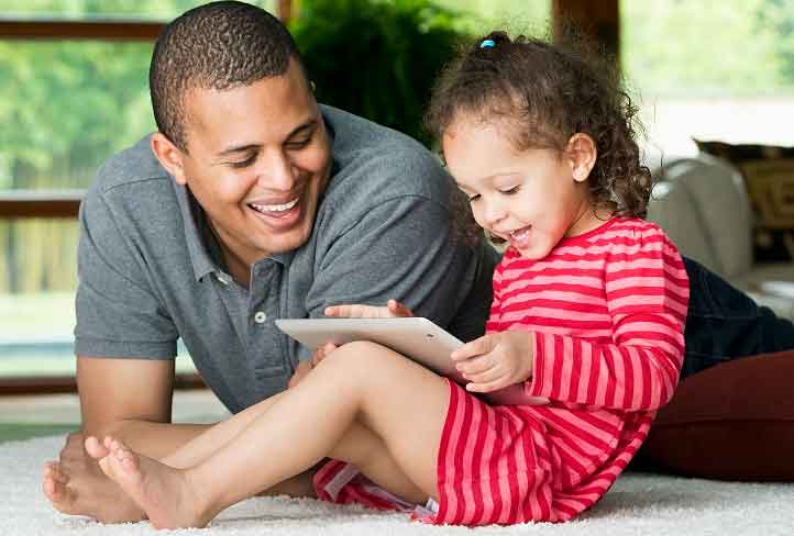 A man watches a child use a tablet