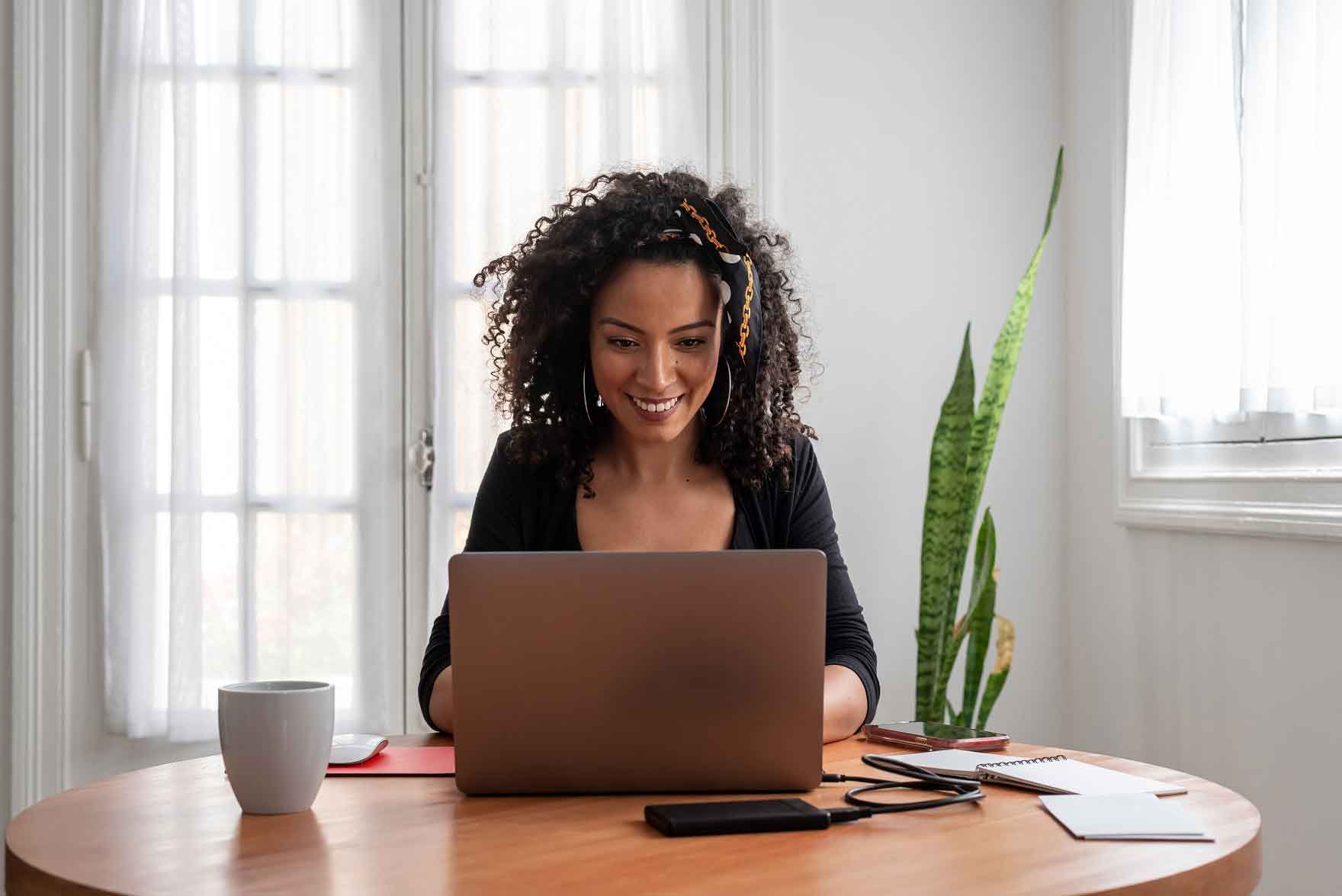 A woman smiles while using a laptop