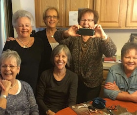 A smiling family sit around a dinner table, posing for a family photo