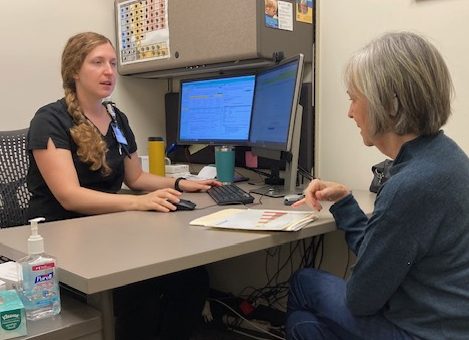 a woman sitting across a desk from her doctor at a cochlear implant activation appointment
