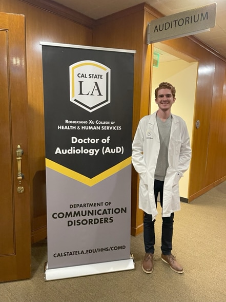 Matthew wearing a doctor’s coat, inspired by his experience with cochlear implant revision surgery and the cochlear implant procedure.