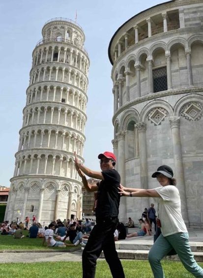 a couple posing for a photo next to the leaning tower of pisa