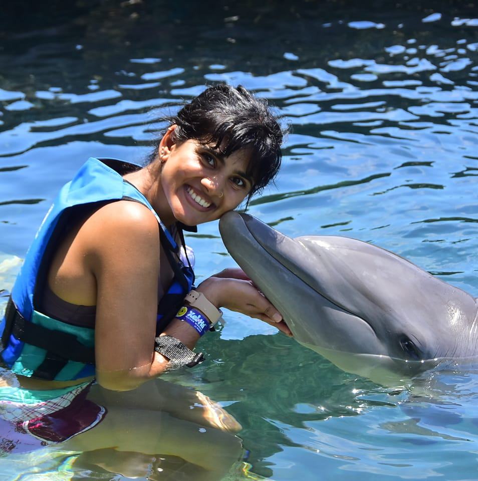 Shobana enjoying a moment in the water with a dolphin, showcasing how living with cochlear implants supports an active and vibrant lifestyle.