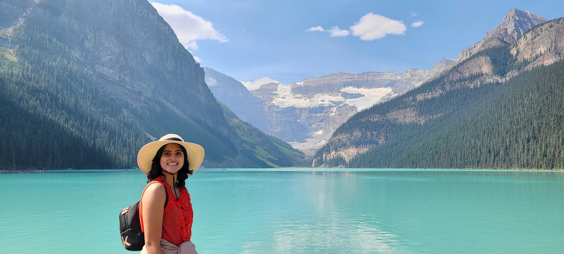 Shobana standing in front of a serene lake with mountains in the background, highlighting her connection to nature while living with cochlear implants.