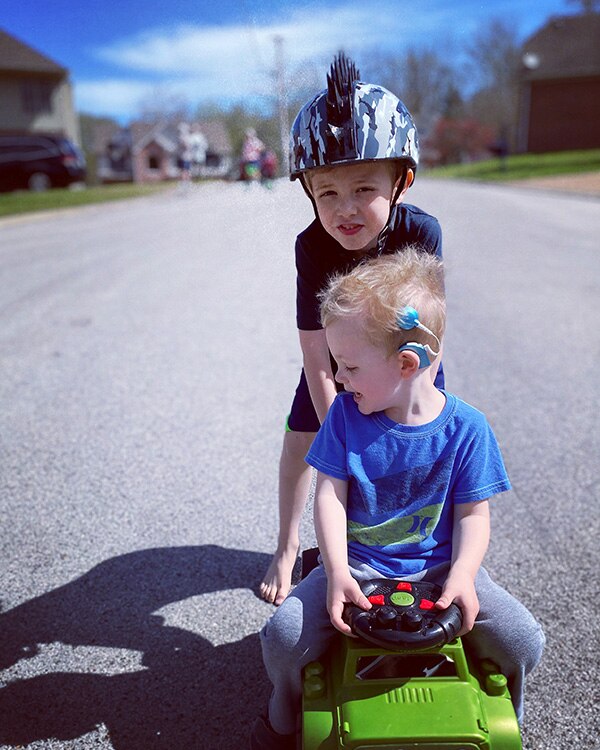 a young child with a cochlear implant plays with his brother