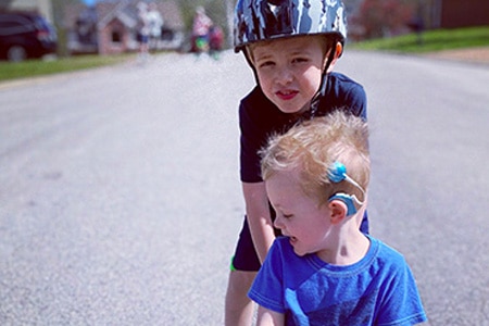 a child cochlear implant recipient skateboarding with sibling 