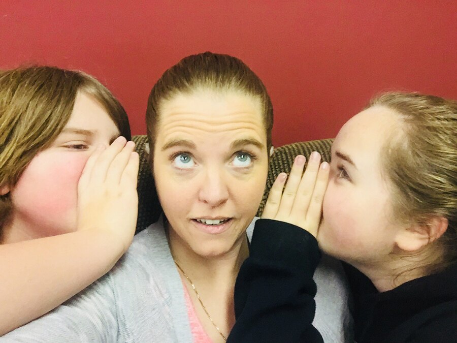 two children whispering to their mother who is a cochelar implant recipient
