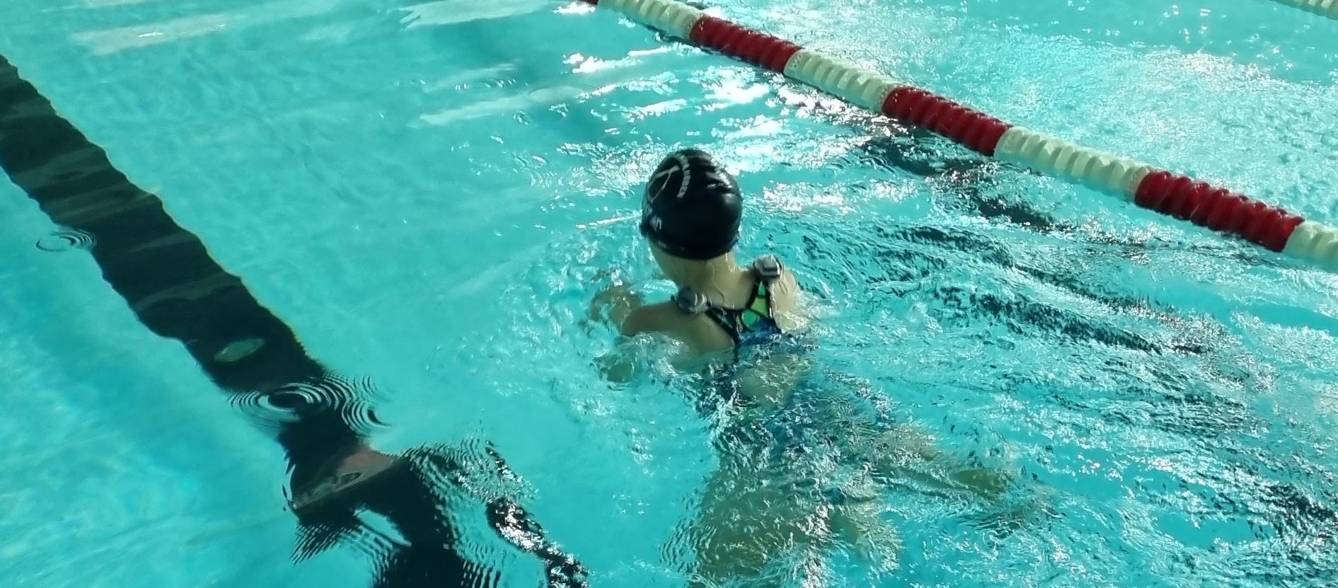 A little girl swims wearing Advanced Bionics waterproof cochlear implants for children
