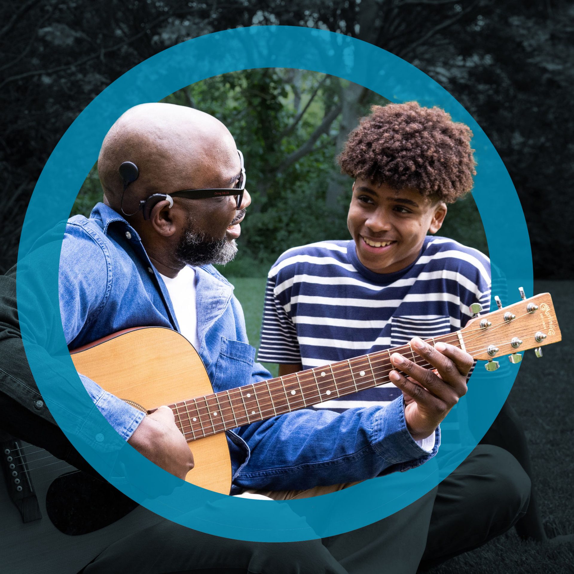 grandfather with cochlear implant plays guitar for his grandchild