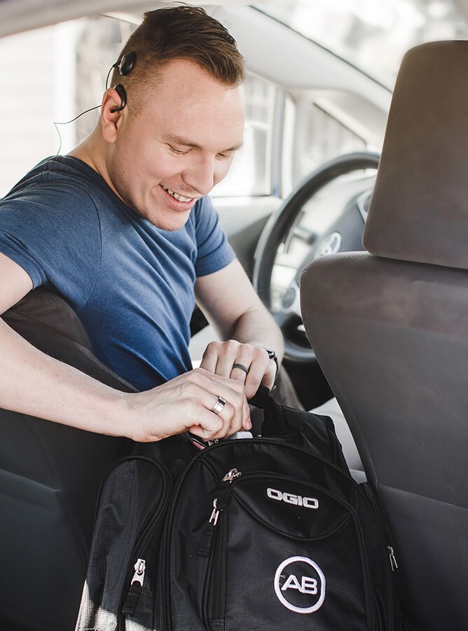 Adult with cochlear implant opens up his bag in a car