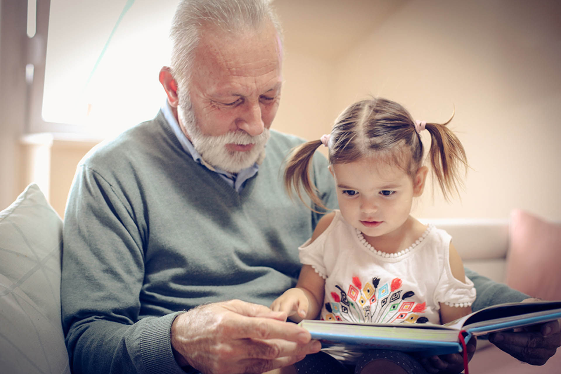 grandfather and granddaughter readying a storybook at home