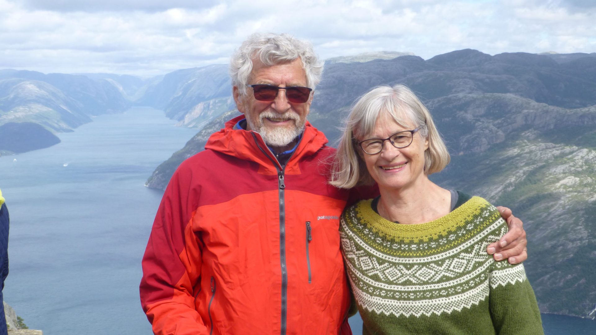 Willy and his wife smiling in front of mountains, showcasing his active life with bimodal hearing.