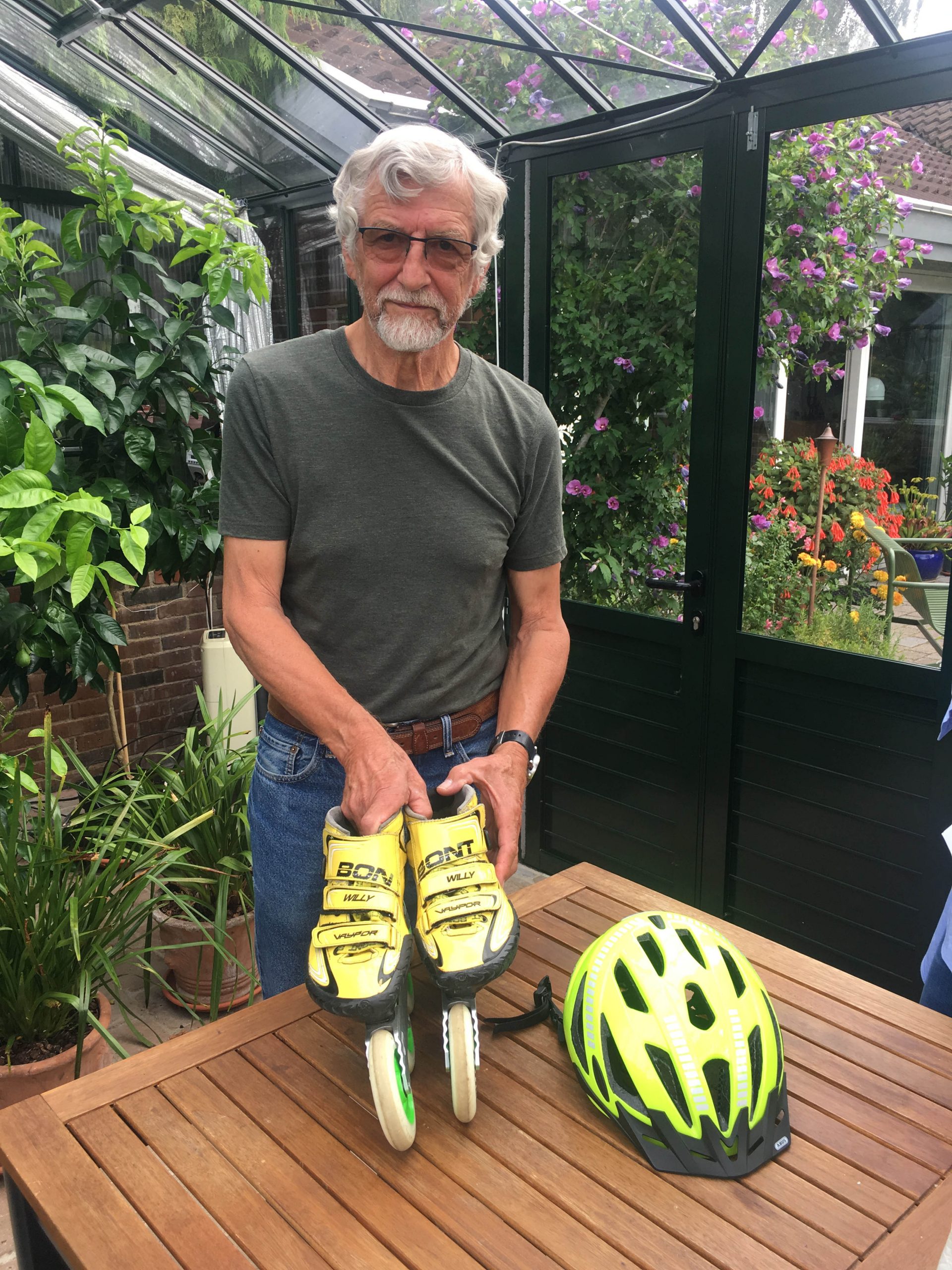 Willy standing next to a table with a helmet and skates, living actively with bimodal hearing.